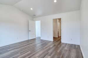 Unfurnished bedroom with vaulted ceiling and hardwood / wood-style floors