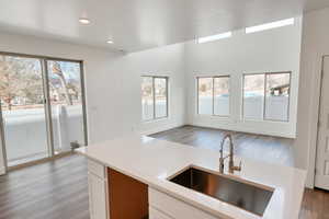 Kitchen with plenty of natural light, sink, white cabinets, and light hardwood / wood-style floors