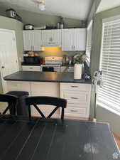 Kitchen with white cabinetry, white range with electric cooktop, plenty of natural light, and a textured ceiling