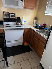 Kitchen featuring white appliances, sink, and light tile patterned floors