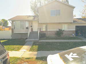 Split level home with a garage, a front yard, and central air condition unit