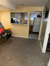 Kitchen with white refrigerator, light colored carpet, and a textured ceiling