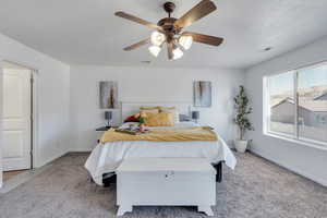 Carpeted bedroom featuring a textured ceiling and ceiling fan