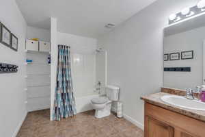 Full bathroom featuring vanity, shower / tub combo, tile patterned floors, and toilet