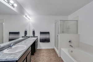 Bathroom featuring tile patterned floors, vanity, independent shower and bath, and a textured ceiling