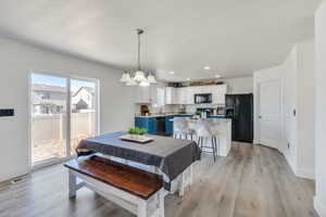 Dining space featuring a chandelier, sink, light hardwood / wood-style flooring, and a textured ceiling