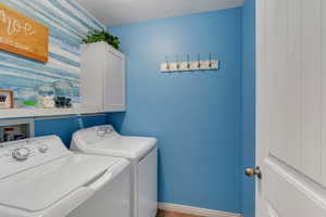 Washroom with separate washer and dryer, cabinets, and a textured ceiling