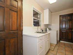 Clothes washing area with washer / clothes dryer, sink, tile walls, cabinets, and light tile patterned floors