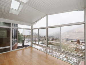 Unfurnished sunroom featuring lofted ceiling with skylight and a mountain view