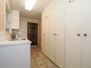 Kitchen featuring white cabinetry, sink, and light tile patterned floors