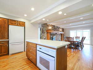 Kitchen with beamed ceiling, white appliances, crown molding, and light hardwood / wood-style floors