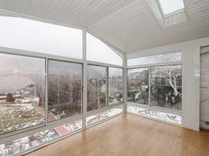 Unfurnished sunroom featuring vaulted ceiling with skylight and a wealth of natural light