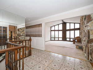 Hallway featuring ornamental molding, vaulted ceiling with beams, and light colored carpet