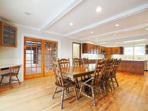 Dining area featuring crown molding, light hardwood / wood-style floors, french doors, and beamed ceiling