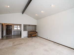 Carpeted spare room featuring beamed ceiling and high vaulted ceiling