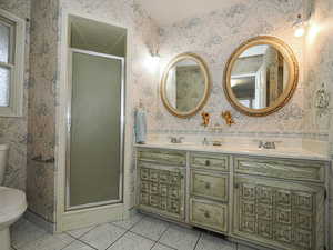 Bathroom featuring an enclosed shower, vanity, tile patterned floors, and toilet