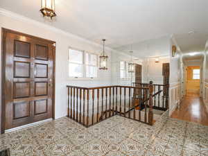 Foyer featuring crown molding, a notable chandelier, and a wealth of natural light