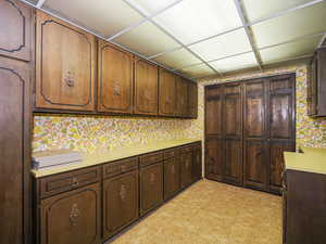 Kitchen featuring a drop ceiling and dark brown cabinetry