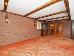 Interior space with brick wall, beam ceiling, and carpet