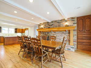 Dining area featuring brick wall, beamed ceiling, and light wood-type flooring