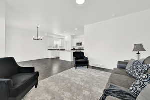 Living room featuring dark hardwood / wood-style flooring, sink, and a notable chandelier