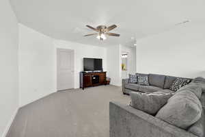 Carpeted living room featuring ceiling fan