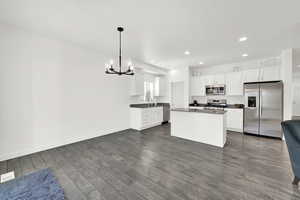 Kitchen with sink, white cabinetry, hanging light fixtures, dark hardwood / wood-style floors, and stainless steel appliances