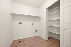 Clothes washing area featuring electric dryer hookup, washer hookup, light tile patterned floors, and a textured ceiling