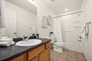 Full bathroom with tile patterned flooring, vanity, shower / tub combo, and toilet