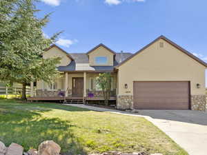 View of front of property featuring a garage, covered porch, and a front lawn