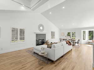 Living room featuring a tiled fireplace, high vaulted ceiling, and light hardwood floors