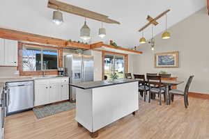 Kitchen with white cabinetry, appliances with stainless steel finishes, decorative light fixtures, and sink