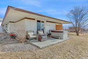 Back of property with a hot tub and a patio area