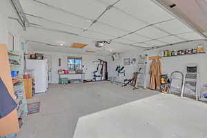 Garage with white refrigerator and a garage door opener