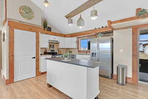 Kitchen featuring sink, decorative light fixtures, light wood-type flooring, stainless steel appliances, and white cabinets