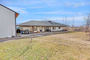 Rear view of property featuring a lawn and a patio area