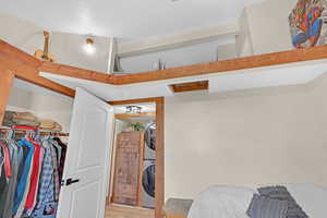 Bedroom with light hardwood / wood-style floors and stacked washing maching and dryer