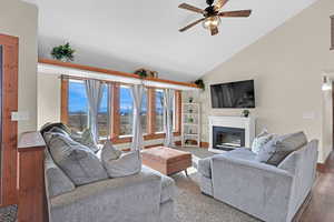 Living room with wood-type flooring, high vaulted ceiling, and ceiling fan