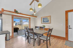 Dining room with high vaulted ceiling and light hardwood / wood-style floors