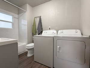 Washroom featuring washer and dryer, dark wood-type flooring, and a textured ceiling