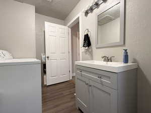 Interior space with dark wood-type flooring, washer / dryer, sink, cabinets, and a textured ceiling