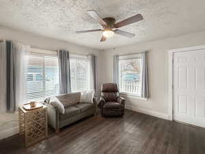 Living area featuring ceiling fan, dark wood-type flooring, and a textured ceiling