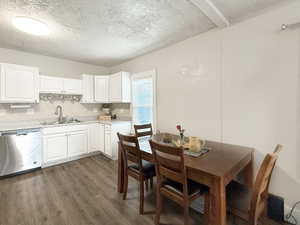 Kitchen with sink, white cabinetry, a textured ceiling, dark hardwood / wood-style flooring, and stainless steel dishwasher