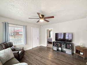 Living room with ceiling fan, dark hardwood / wood-style flooring, and a textured ceiling