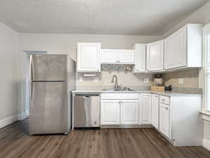 Kitchen featuring sink, tasteful backsplash, dark hardwood / wood-style flooring, stainless steel appliances, and white cabinets