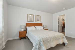 Bedroom featuring a walk in closet, a closet, a textured ceiling, and carpet flooring