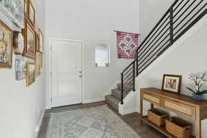 Entrance foyer featuring a towering ceiling and dark hardwood / wood-style flooring