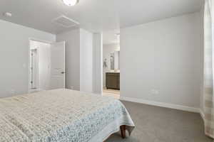 Bedroom with ensuite bath and light colored carpet