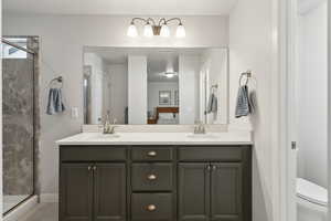 Bathroom with a shower with door, vanity, and toilet