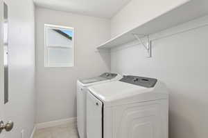 Laundry area with light tile patterned floors and washer and clothes dryer